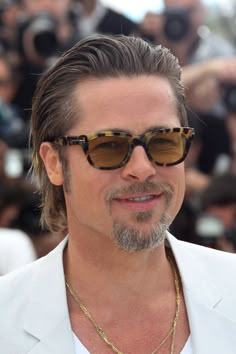 a man with sunglasses on standing in front of photographers