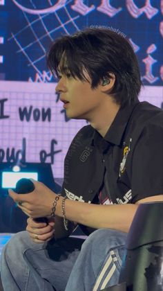 a young man sitting down holding a remote control