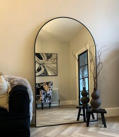 a living room with a black couch and large mirror on the wall next to it