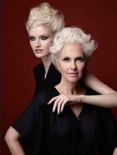 two women in black dresses posing for the camera with their arms on each other's shoulders