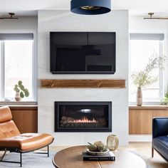 a living room with two couches and a television mounted on the wall above it