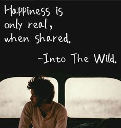 a man sitting in front of a window with a quote on it that says happiness is only real, when shared into the wild