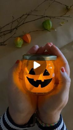 a person holding up a pumpkin jar in front of their face with the light on