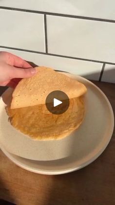 a person is holding a piece of bread on a plate