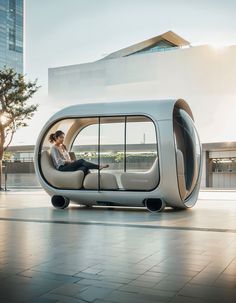 a woman sitting on top of a couch in the shape of a pod like vehicle