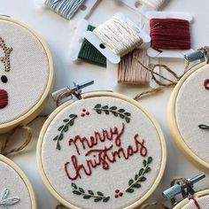 embroidered christmas ornaments on white table with red and green thread