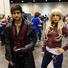 two people dressed in costumes standing next to each other at a convention or convention hall