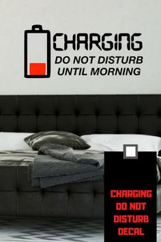 a bed with a black headboard sitting next to a wall that says charging do not disturb decal