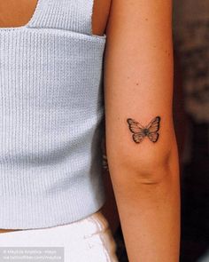 a woman's arm with a small butterfly tattoo on the left side of her arm