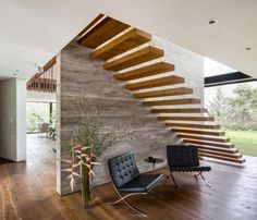 a living room with wooden floors and stairs in the wall next to a black chair