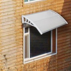 an awning on the side of a brown building with a cat sitting in it's window