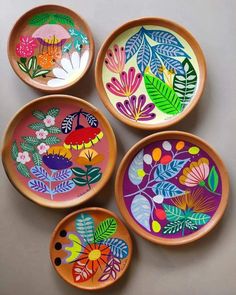 four wooden bowls with painted designs on them