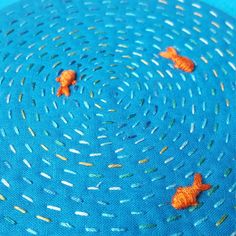 three orange fish are swimming in the blue water with small white dots on it's surface