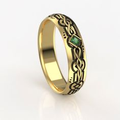 a gold wedding ring with an emerald stone in the center and celtic designs on it