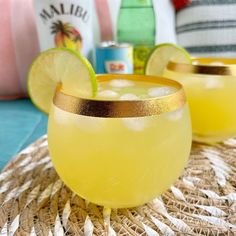 two glasses filled with yellow liquid and lime slices