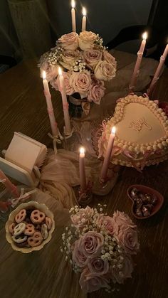 a table topped with lots of cake covered in frosting next to candles and flowers