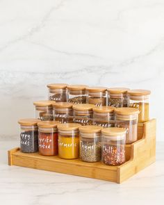 a wooden spice rack with twelve jars filled with different spices on top of each other