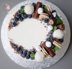 a cake decorated with blueberries, marshmallows and other toppings on a white plate