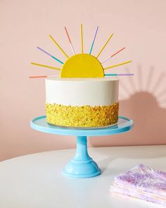 a white cake with yellow and blue frosting sitting on top of a table next to a napkin