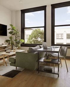 a living room filled with furniture next to two large windows and a flat screen tv