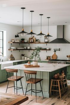 a kitchen with green cabinets and wooden stools in front of an island counter topped with potted plants