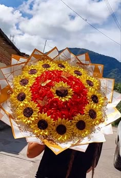 a woman holding up a large bouquet of sunflowers