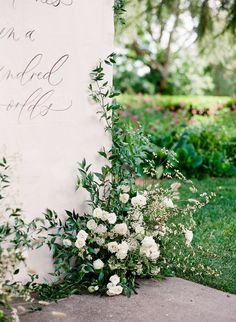 flowers and greenery on the ground next to a sign