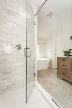 a bathroom with a glass shower door and wooden cabinet in the corner next to it