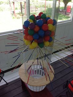 a birdcage filled with lots of colorful balls on top of a wooden table