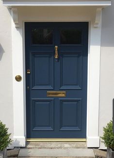 a blue front door with two planters on either side and one potted plant