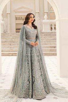 a woman in a blue and silver lehenga stands on steps with her arms crossed