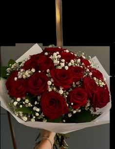 a bouquet of red roses with baby's breath in the middle is held by a woman