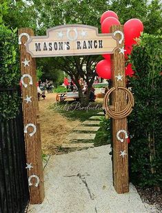 the entrance to mason's ranch is decorated with red and white balloons, which are hung on wooden posts