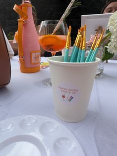 there is a cup with pens in it on the table next to some wine glasses