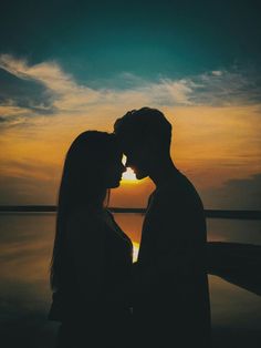 two people standing next to each other with the sun setting behind them