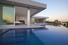 a large swimming pool next to a modern house with glass doors and windows on the side