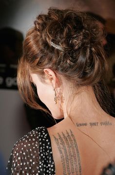 the back of a woman's neck with tattoos on her left shoulder and right arm