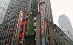 people are standing in front of the radio city building on a snowy day with snow falling