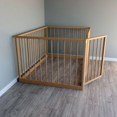 a wooden crib sitting in the corner of a room next to a gray wall