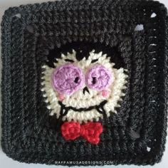 a crocheted square with a smiling face and bow tie on it's side