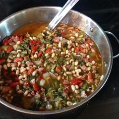 a pot filled with beans and vegetables on top of a stove