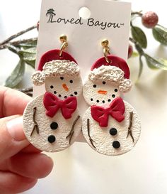 a pair of snowmen wearing red hats and bow ties are hanging from the back of earrings