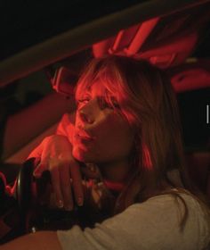 a woman sitting in the back seat of a car with her hand on the steering wheel