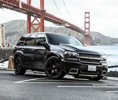 a black suv parked in front of the golden gate bridge