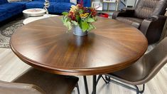 a wooden table with chairs around it in a room filled with couches and tables