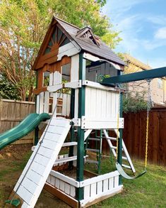 a wooden swing set with a green slide