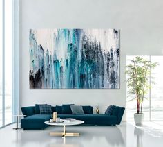 a living room with a large painting on the wall and a blue couch in front of it