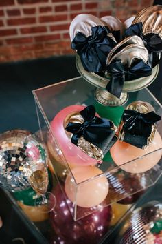 an assortment of shoes and other items in a display case on a table with brick wall