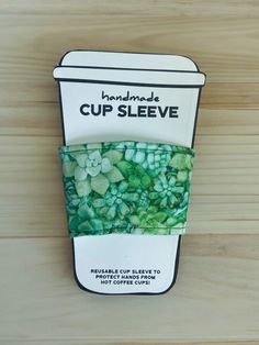 the cup sleeve is made from recycled materials and has green flowers on it's side