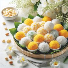 a basket filled with white and yellow desserts next to flowers on top of a table